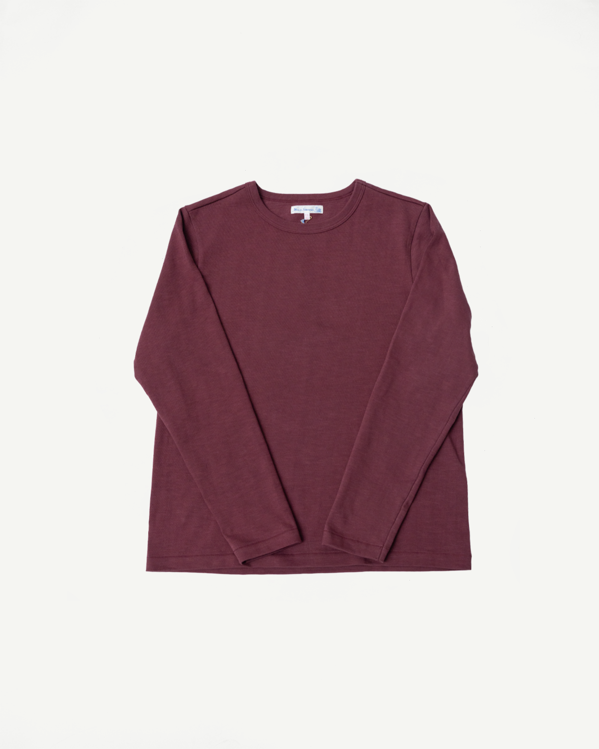 Flat lay of the front of a maroon long-sleeve crewneck shirt with a visible neck tag.