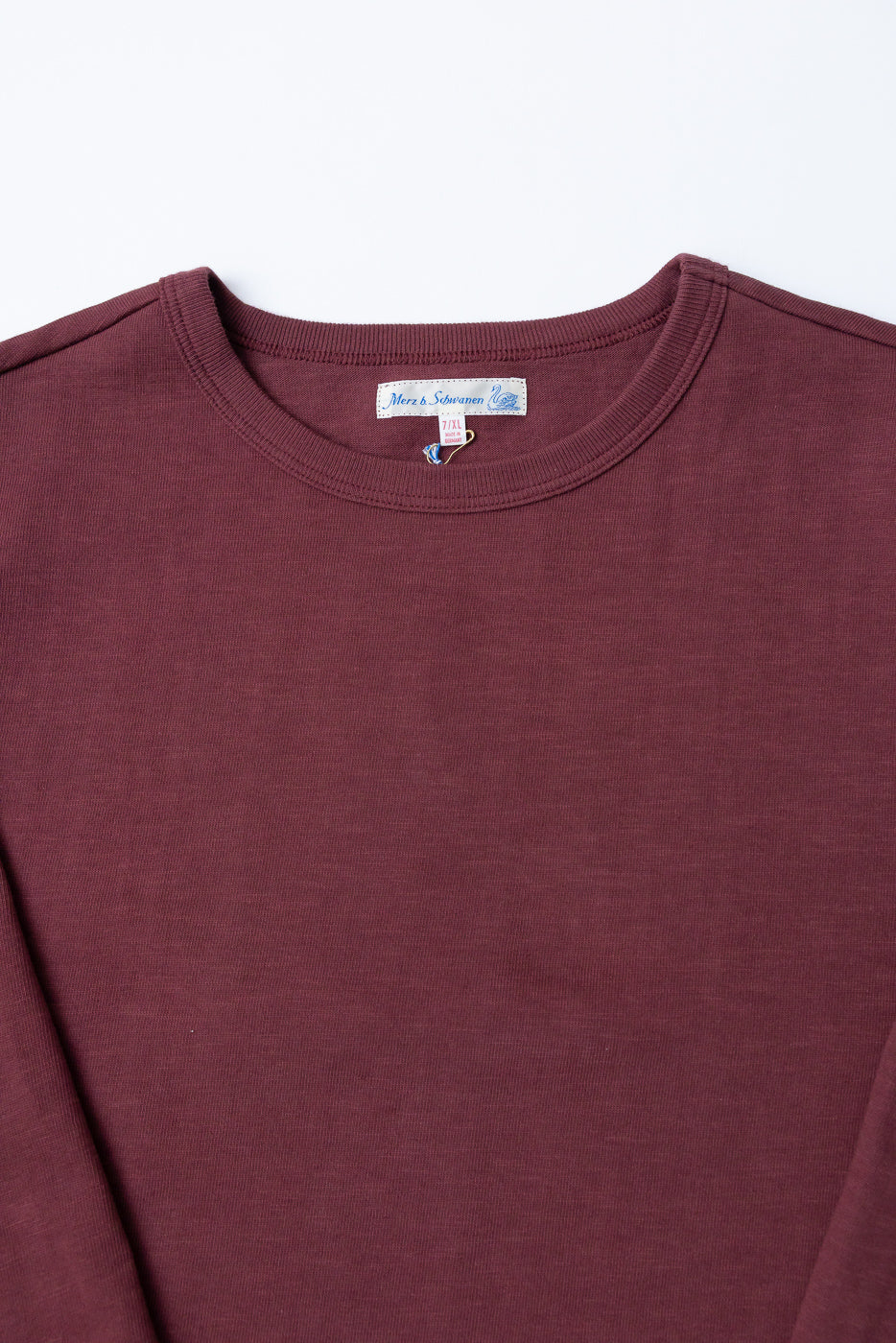 Close-up of the front neckline and tag of a burgundy crewneck sweatshirt.