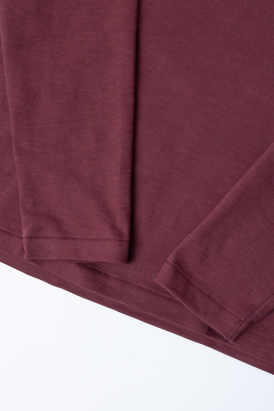 Close-up of the front texture and hem of a maroon long-sleeve shirt.