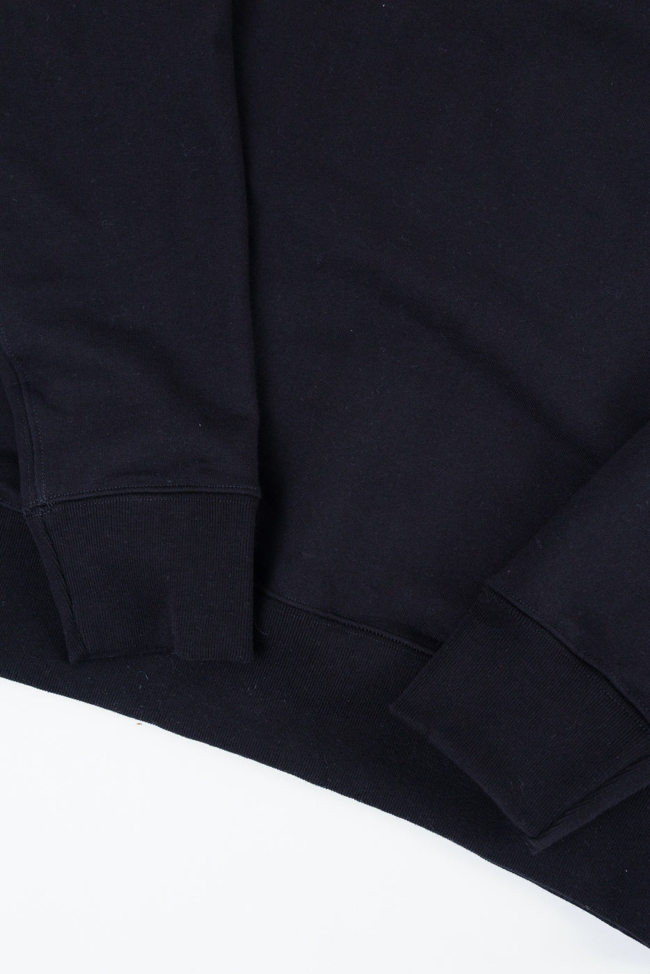 Close-up of the front bottom hem and cuffs of a black sweatshirt.