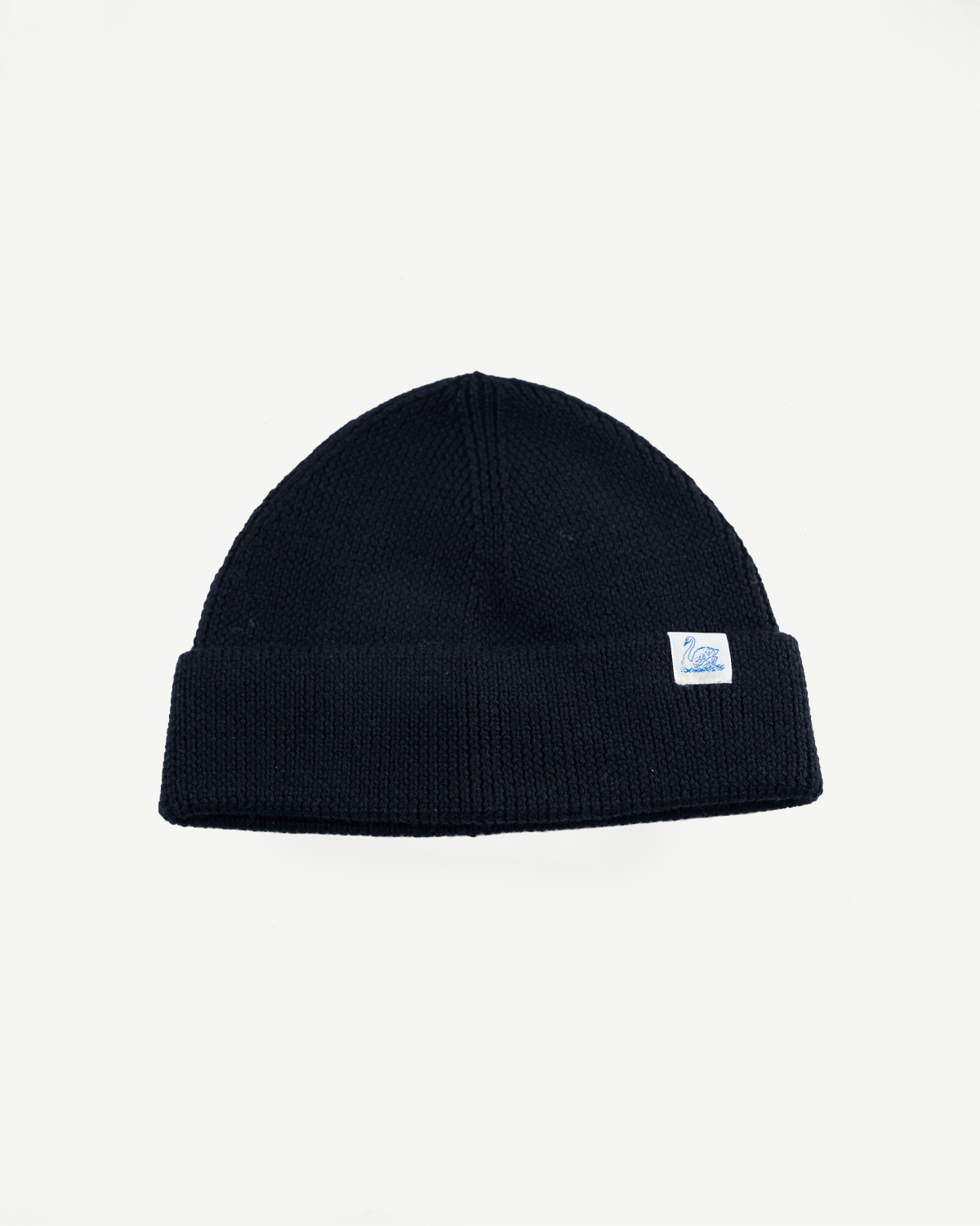 Front flat lay of Merz b. Schwanen deep black ribbed merino wool beanie, cuff and logo tag visible