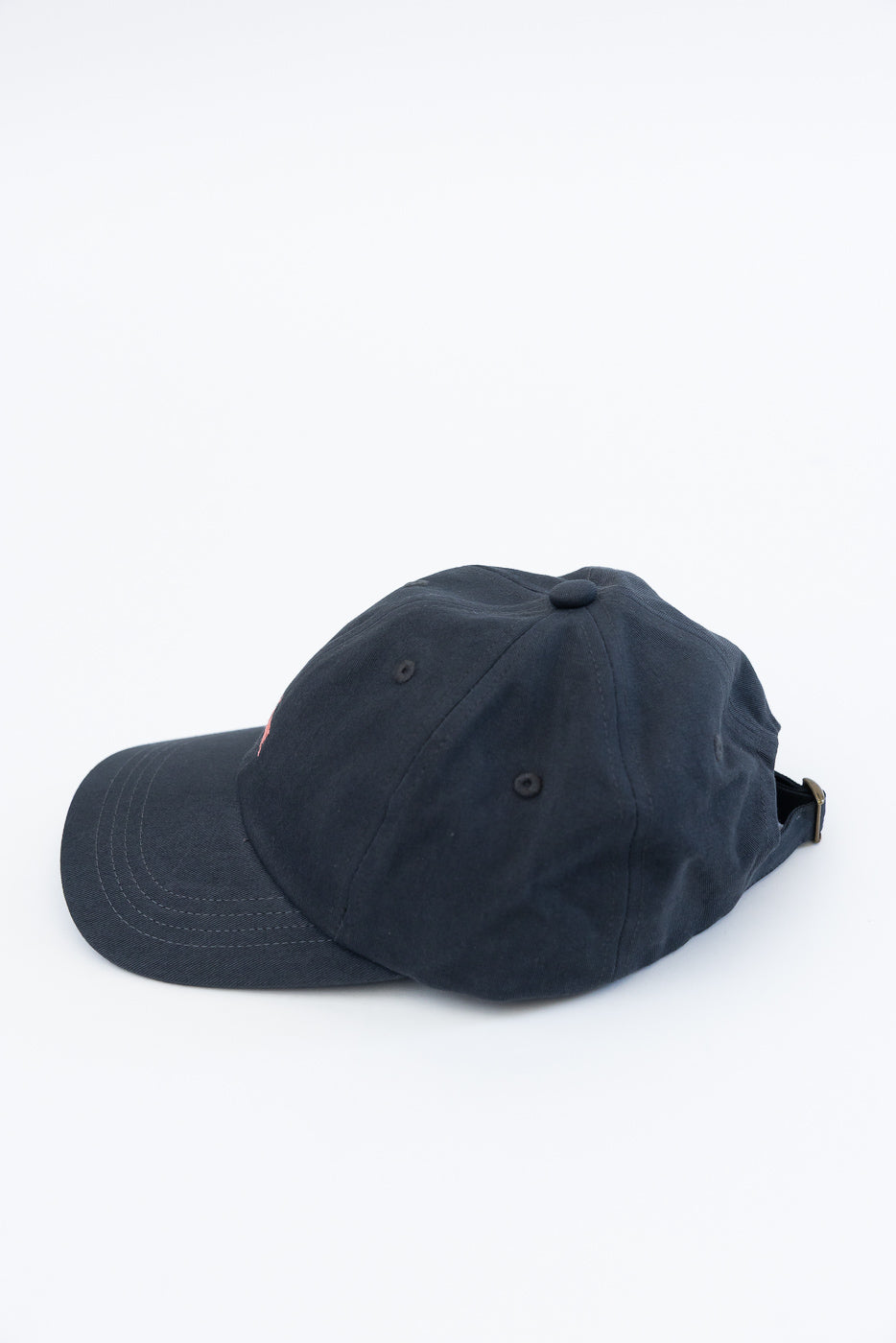 Side view close-up of charcoal cotton twill cap with metal adjustable strap and top button