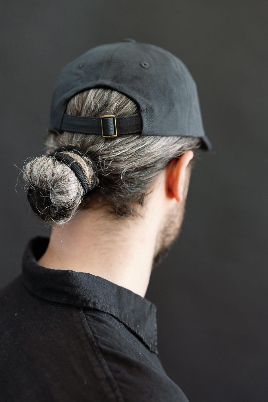 Close-up rear view of male model, 5'9”, 165lbs, athletic build, wearing charcoal cotton twill cap showing back strap detail.
