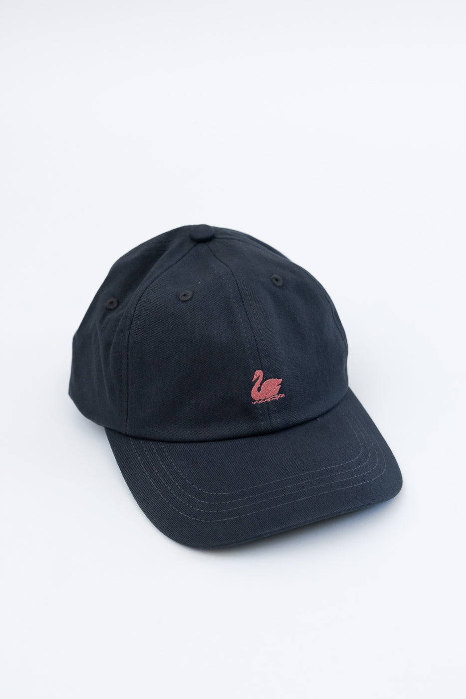 Front view close-up of a charcoal cotton twill cap with rosewood swan logo embroidery.