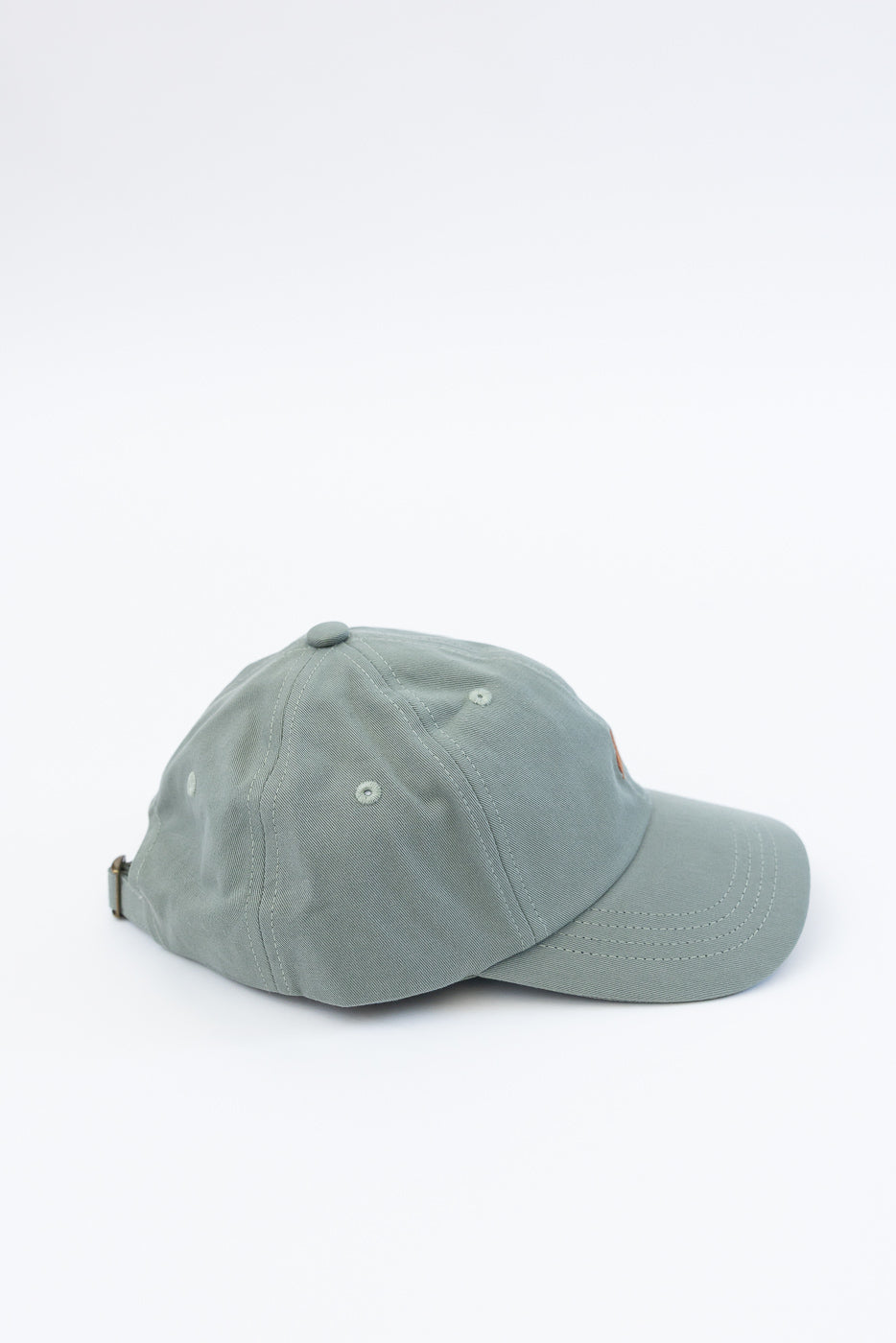 Cotton twill cap in light army green, flat lay right side view showing panel seams and eyelets.
