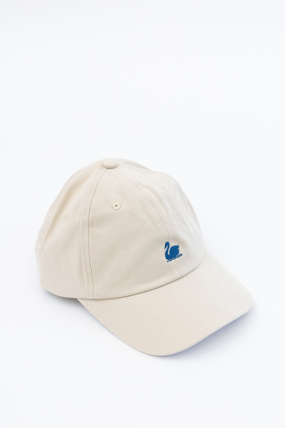 Front angled close-up of light khaki cotton twill cap with blue swan logo embroidery