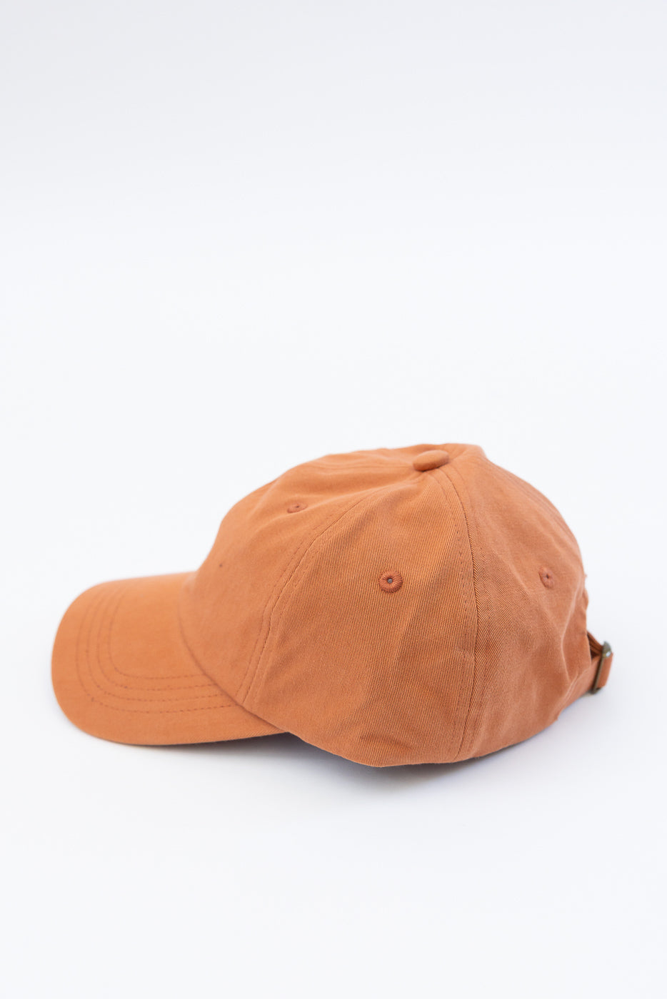 Side view close-up of pumpkin orange cotton twill cap showing back and left side details.