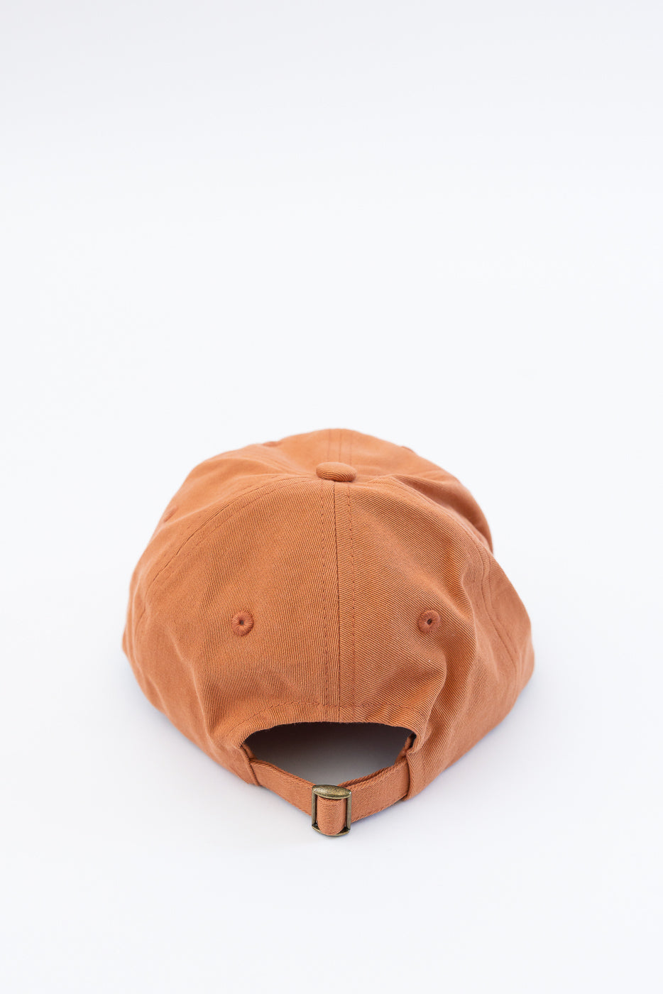 Back view close-up of pumpkin orange cotton twill cap showing adjustable strap detail.