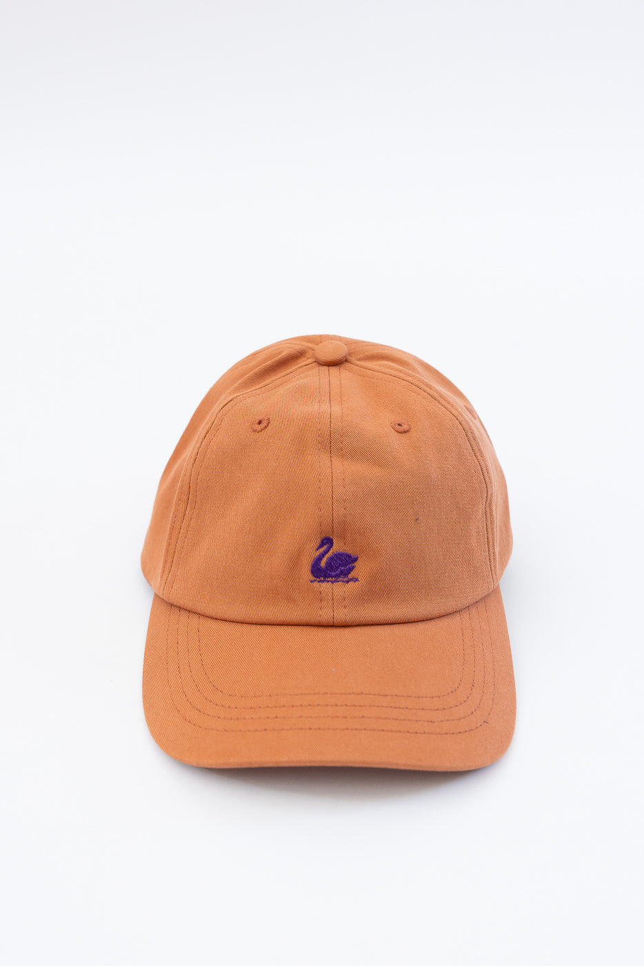 Front close-up of pumpkin orange cotton twill cap with purple swan logo embroidery