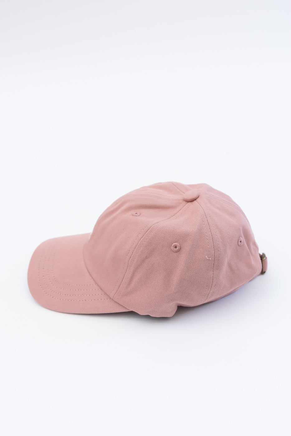 Side view flat lay of rosewood cotton twill cap showing crown, eyelets, and curved brim.