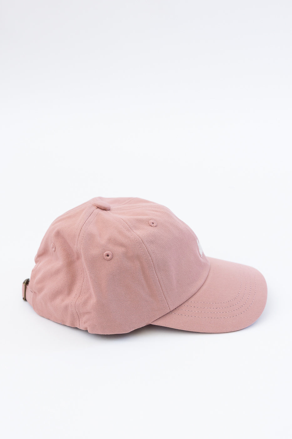 Close-up side view of rosewood pink cotton twill cap, showing fabric texture and stitching.