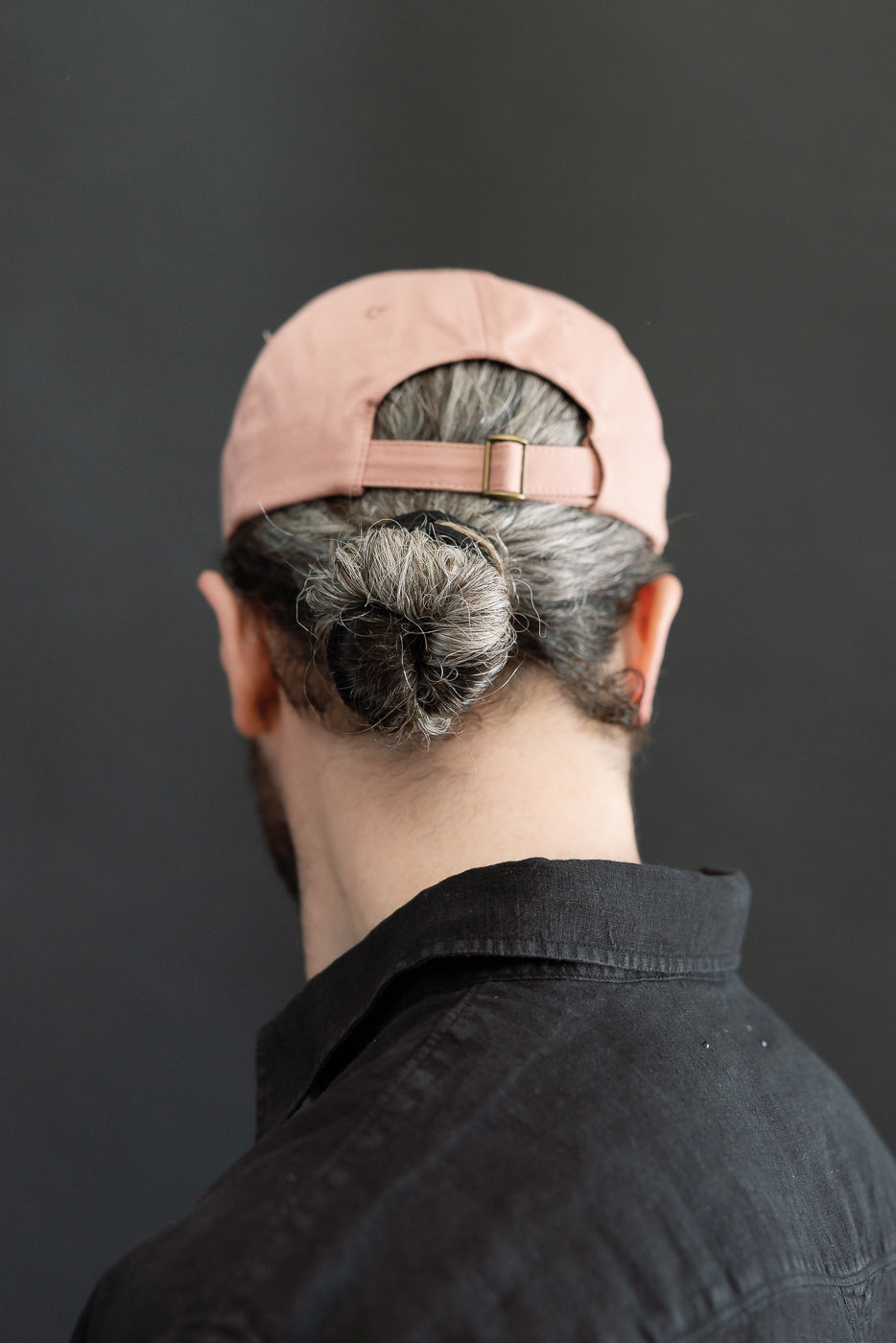 Back close-up of rose pink cotton twill cap, male model 5'9 165lbs athletic, showing strap and buckle detail.