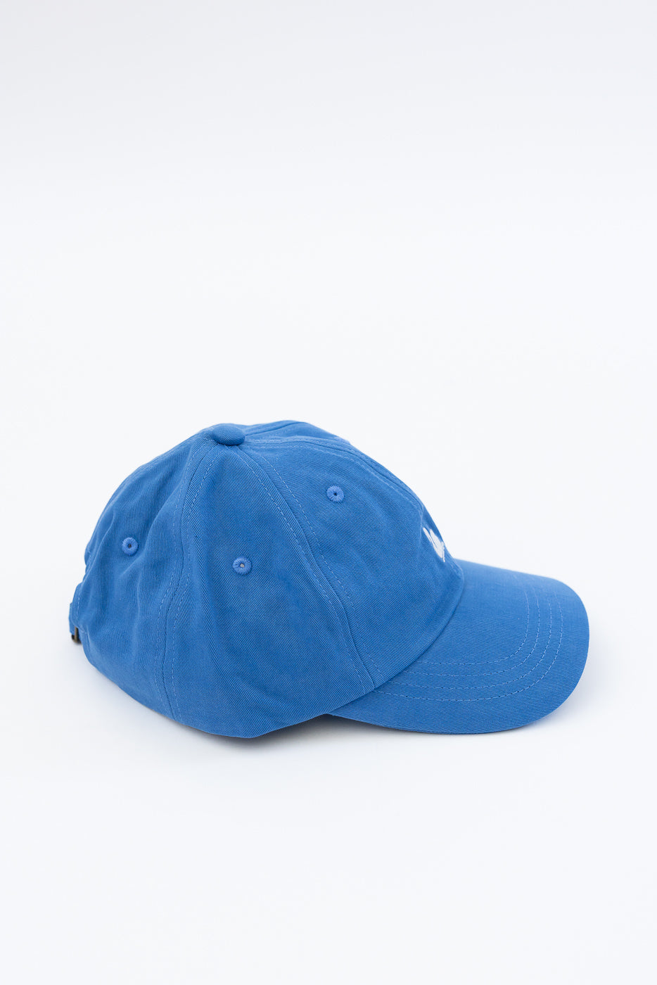 Side view close-up of blue cotton twill cap with embroidered logo, showing crown and brim details