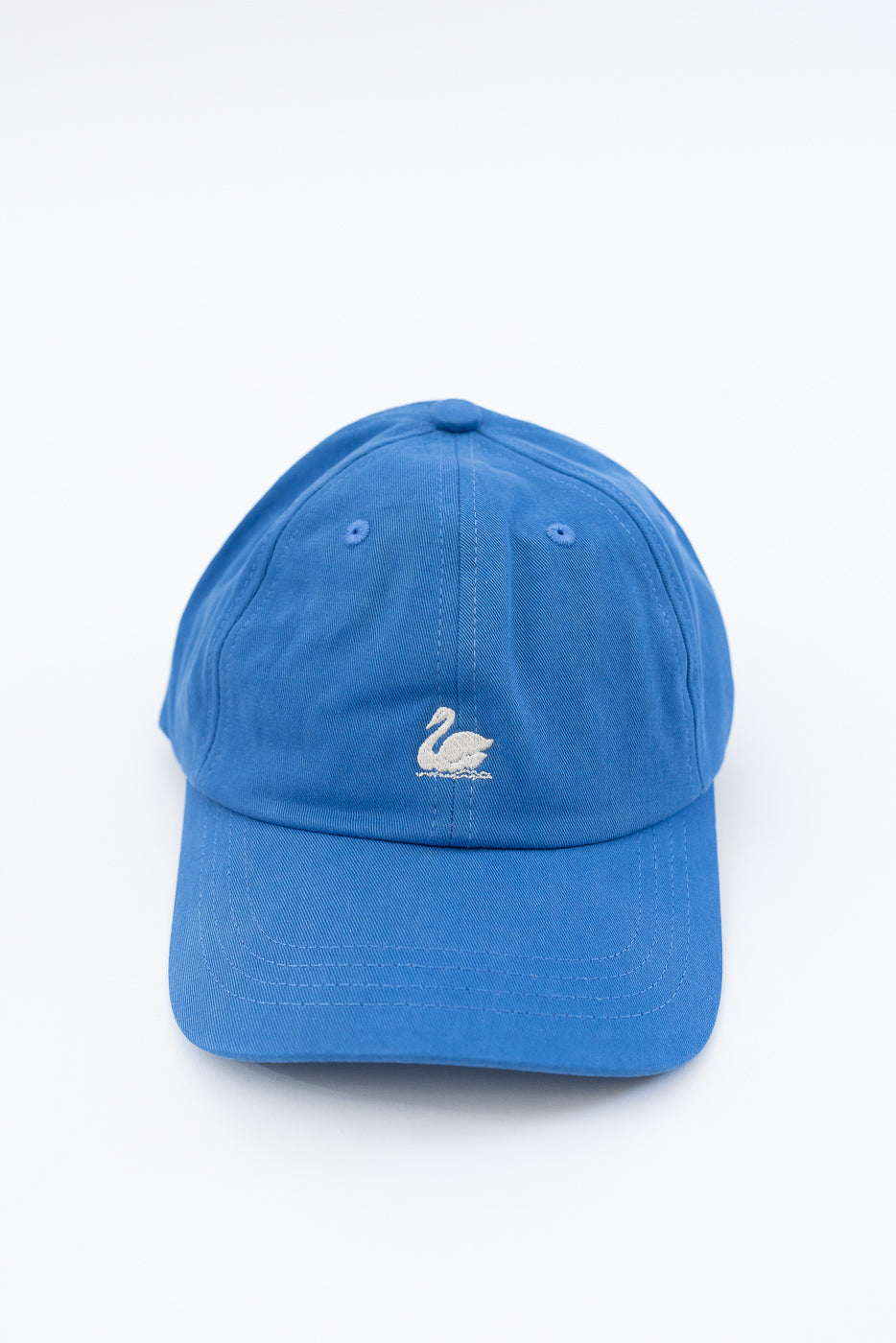 Close-up front view of blue cotton twill cap with white swan logo embroidery.