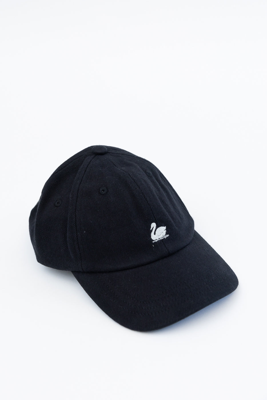 Front angled close-up of deep black cotton twill cap with white swan logo embroidery.