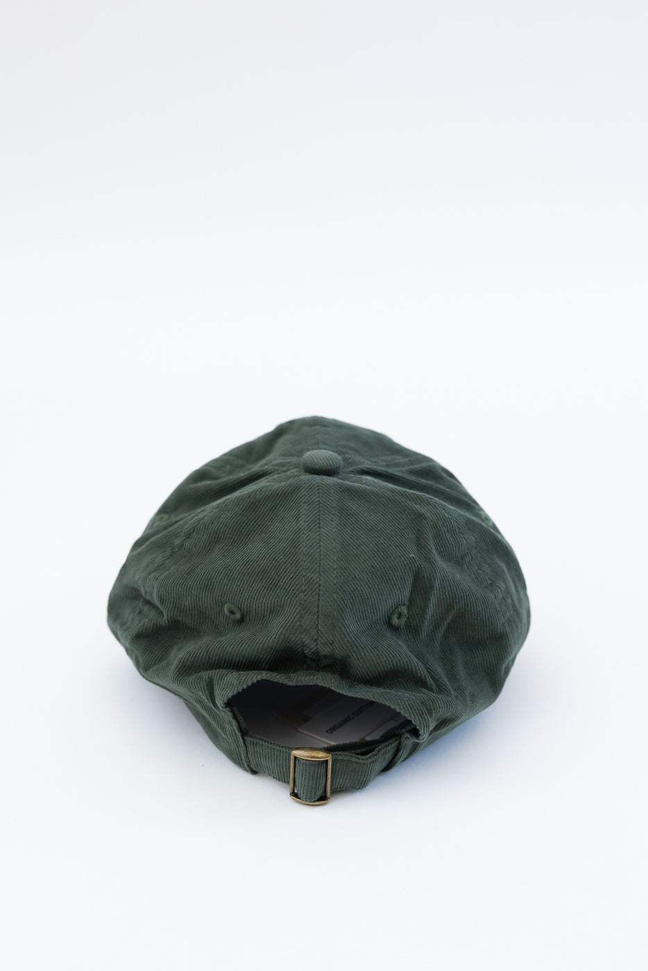 Close-up back view of a forest green cotton corduroy cap with adjustable strap and metal buckle.