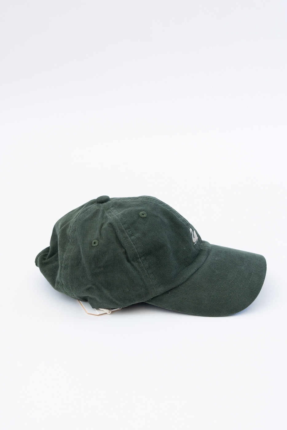 Side view close-up of forest green cotton corduroy cap with swan logo, showing brim and textured fabric.
