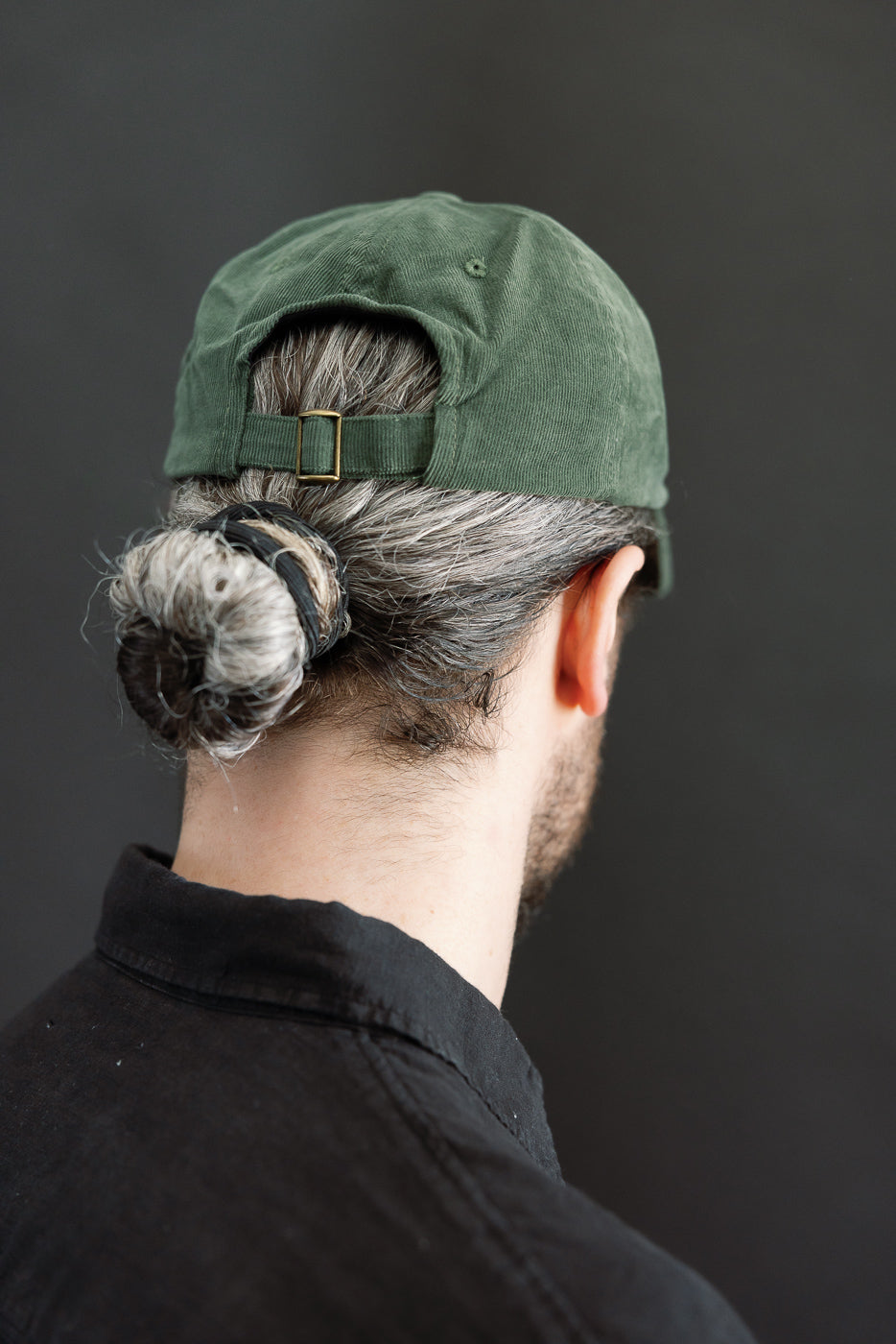 Rear close-up of green corduroy cap, adjustable strap visible, on male model 5'9