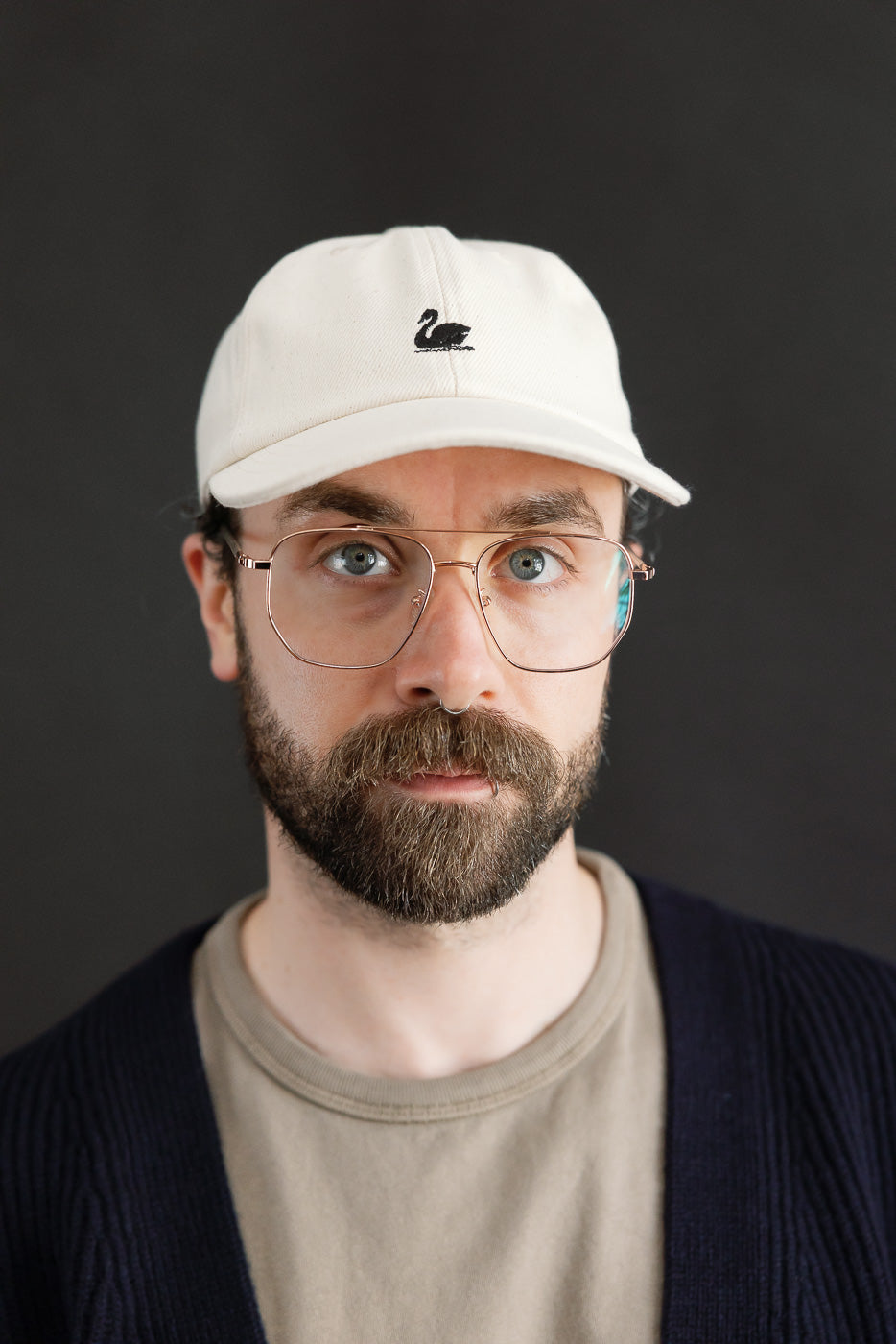 Close-up front view of Merz b. Schwanen Swan Logo cotton twill cap in nature on male model, 5'9