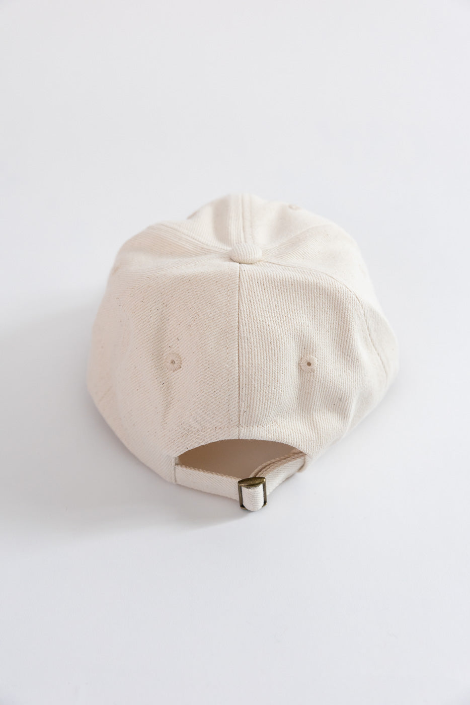 Close-up of Merz b. Schwanen natural cotton twill cap, back view with strap and metal buckle.
