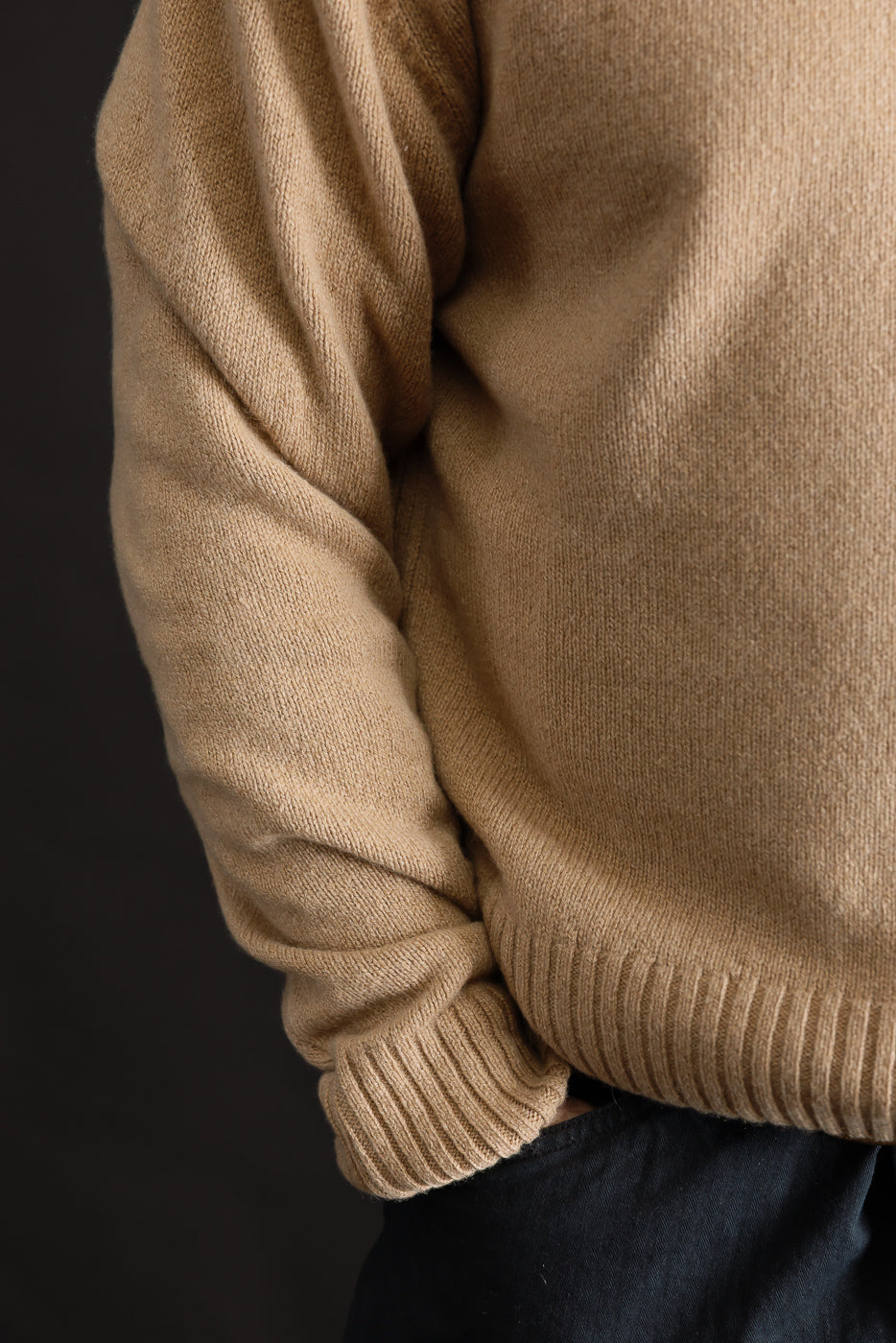 Close-up of male model’s right side wearing toffee recycled cashmere sweater, showing ribbed cuff and hem detail, sleeve and body texture. Male model is 5'9