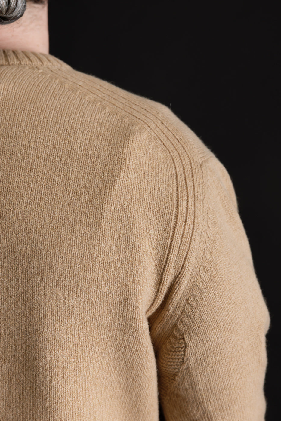 Close-up of back shoulder seam and knit texture on toffee recycled cashmere sweater, male model, athletic build.