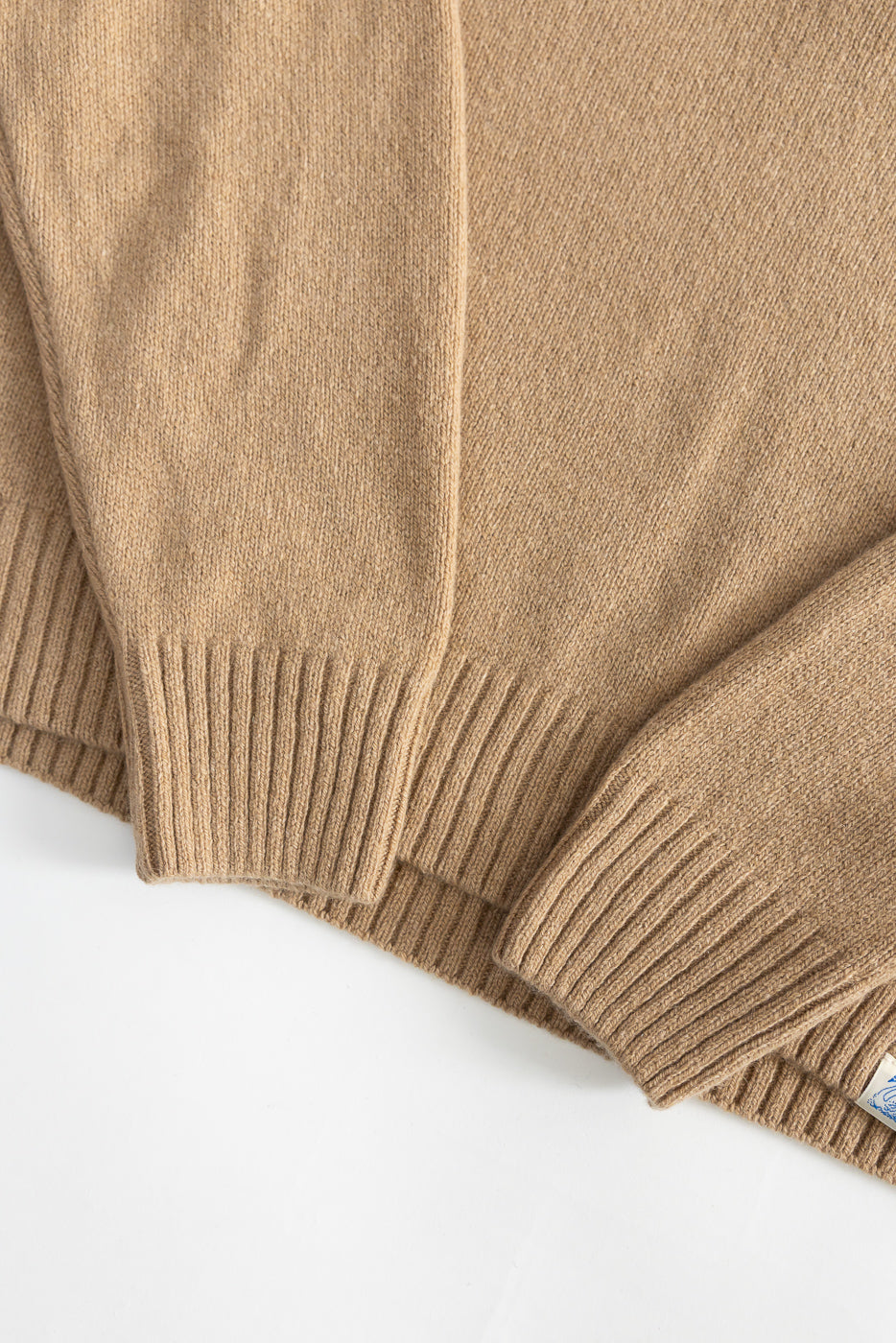 Close-up of front hem and sleeves of toffee recycled cashmere sweater, ribbed texture visible.