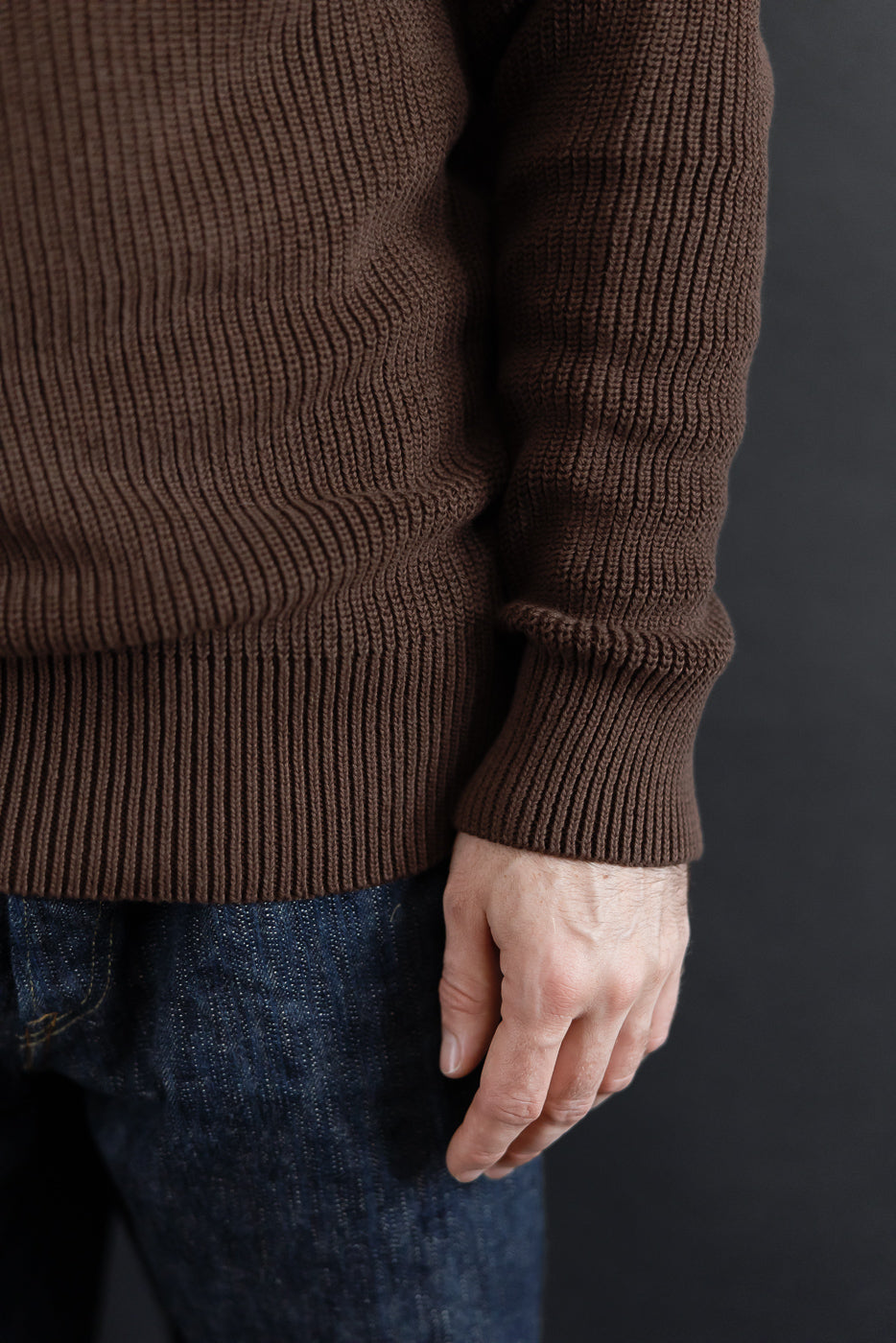 Close-up side view of a brown ribbed knit sweater on a male model, 5'9