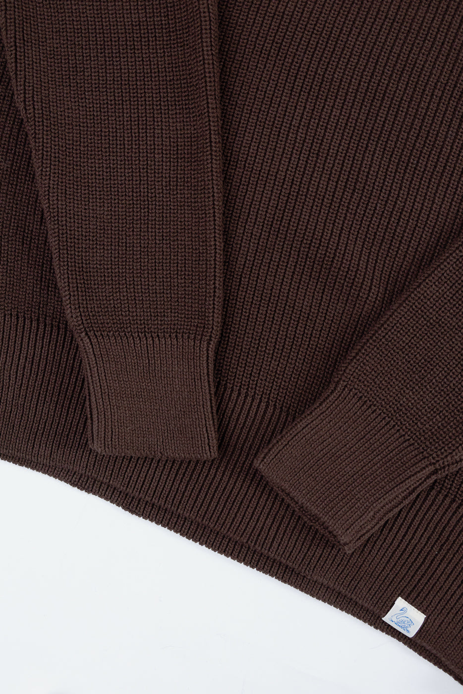 Close-up of the front texture and ribbed cuffs of a brown knit sweater.