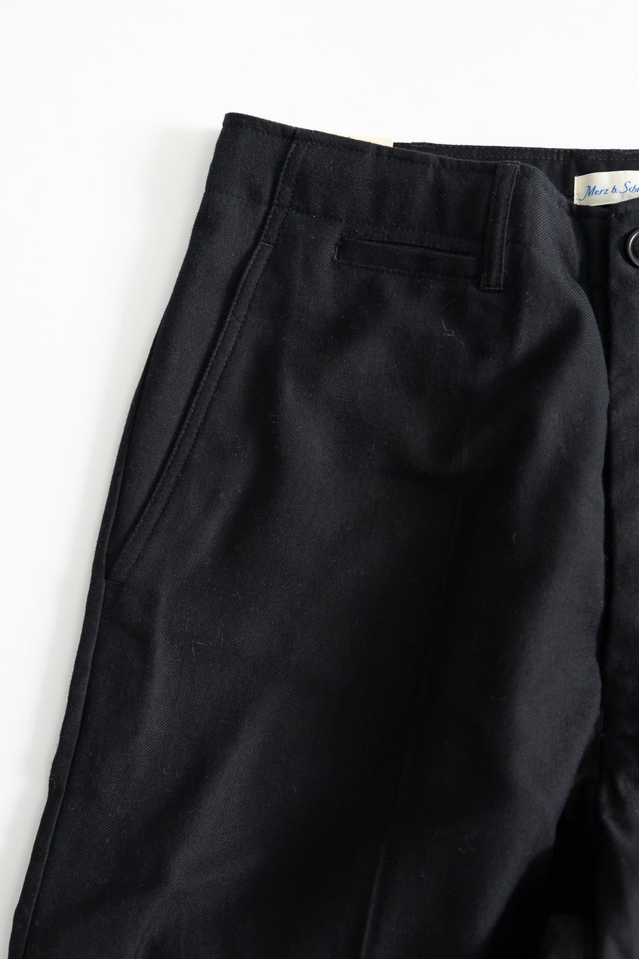 Close-up of wool cotton worker chino, front upper section with front pockets and button waist in deep black.