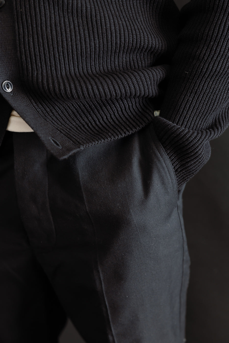 Close-up of front left side of deep black wool cotton chino on male model, pleat details visible, model is 5'9