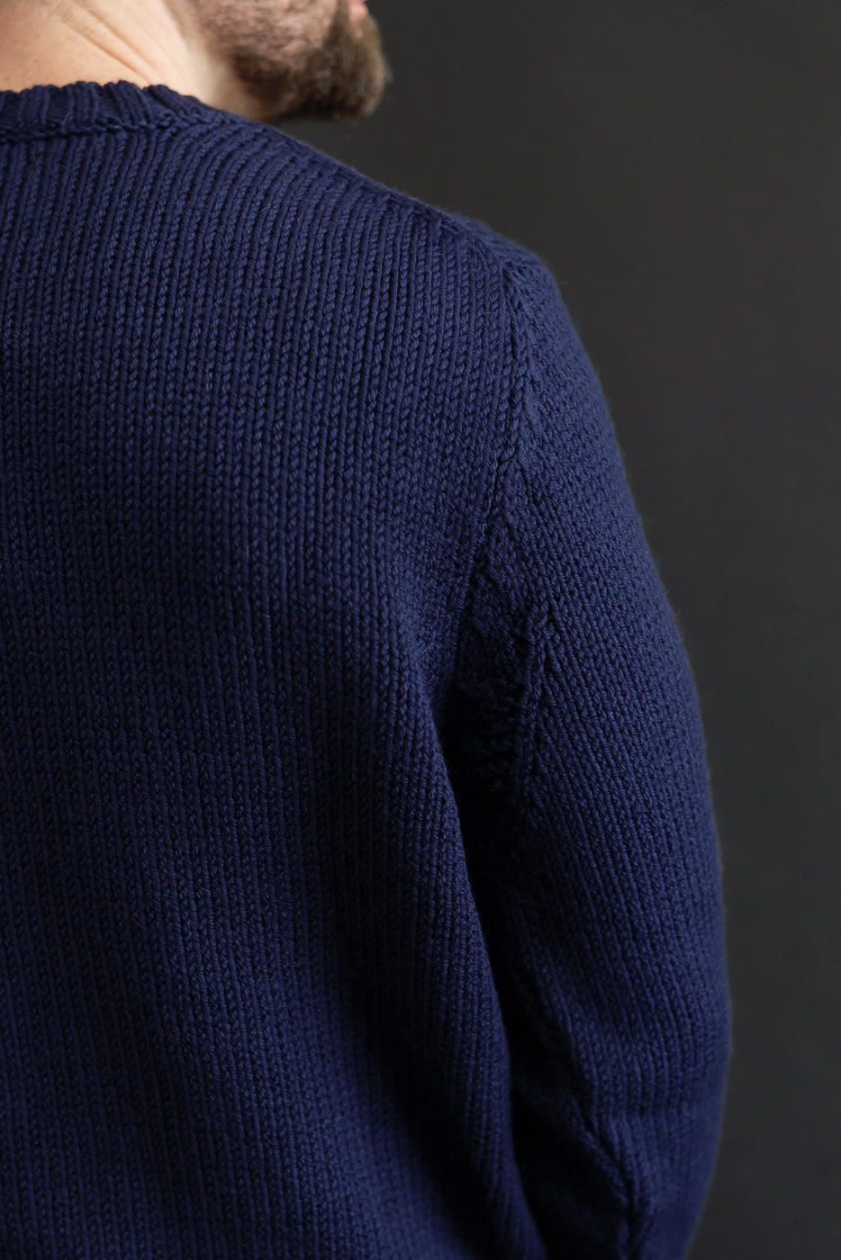 Close-up back view of a navy ribbed knit sweater on a male model, 5'9