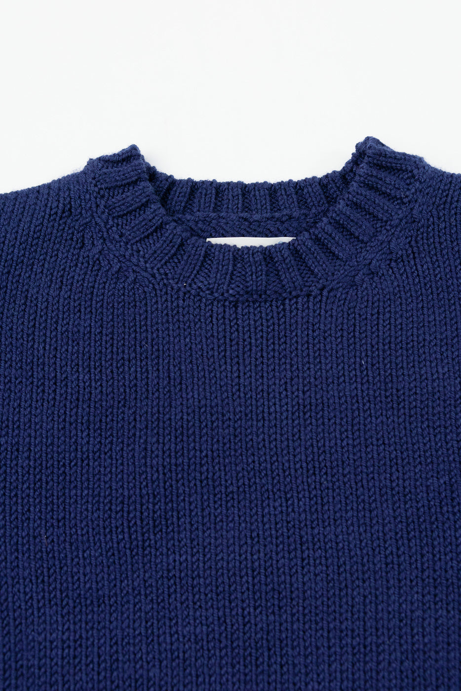 Close-up front view of a navy blue knit sweater showing the ribbed crewneck collar texture.