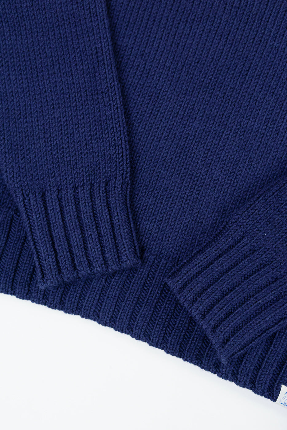Close-up of the ribbed cuffs and knit texture on the front of a navy blue sweater.