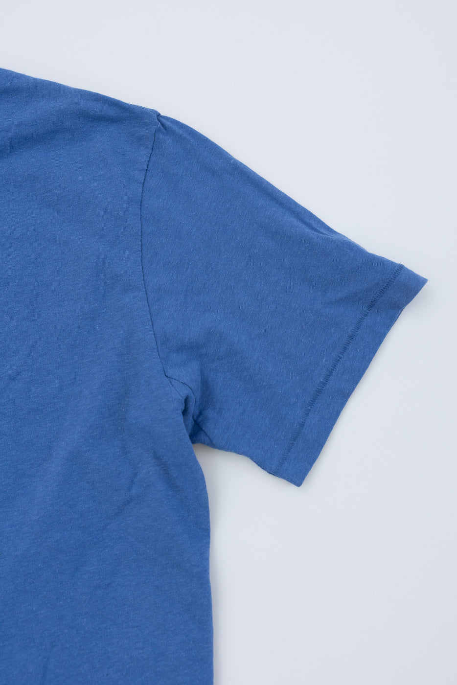 Close-up of right sleeve and shoulder seam, front side, blue cotton hemp t-shirt flat lay