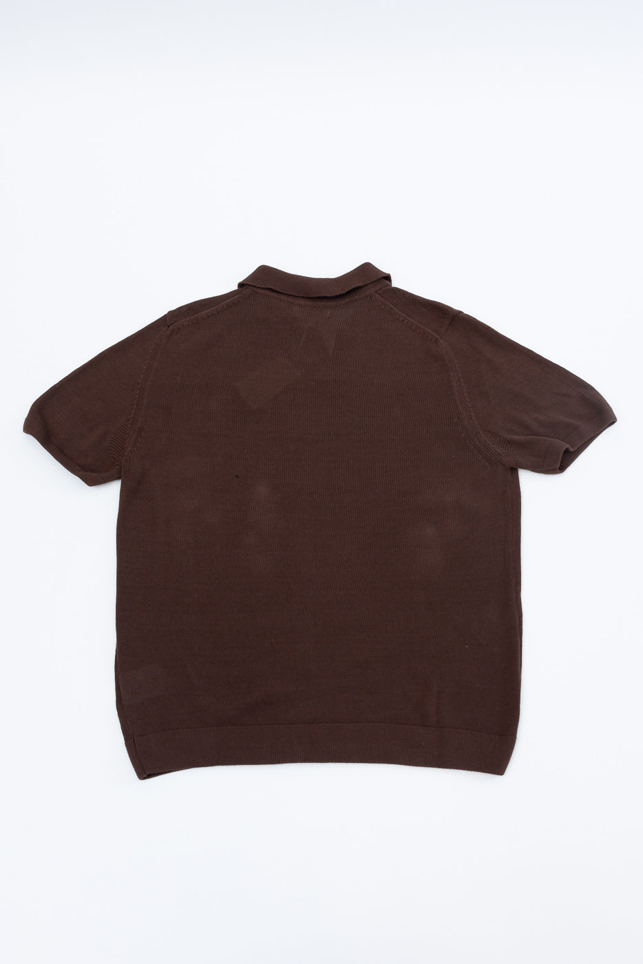 The KNITPOLO02.192.7 - Cotton Short Sleeve Polo Shirt, All Plant Based - Chocolate, is shown laid flat, highlighting its soft, breathable organic knit texture and subtle swan embroidery above the hem.