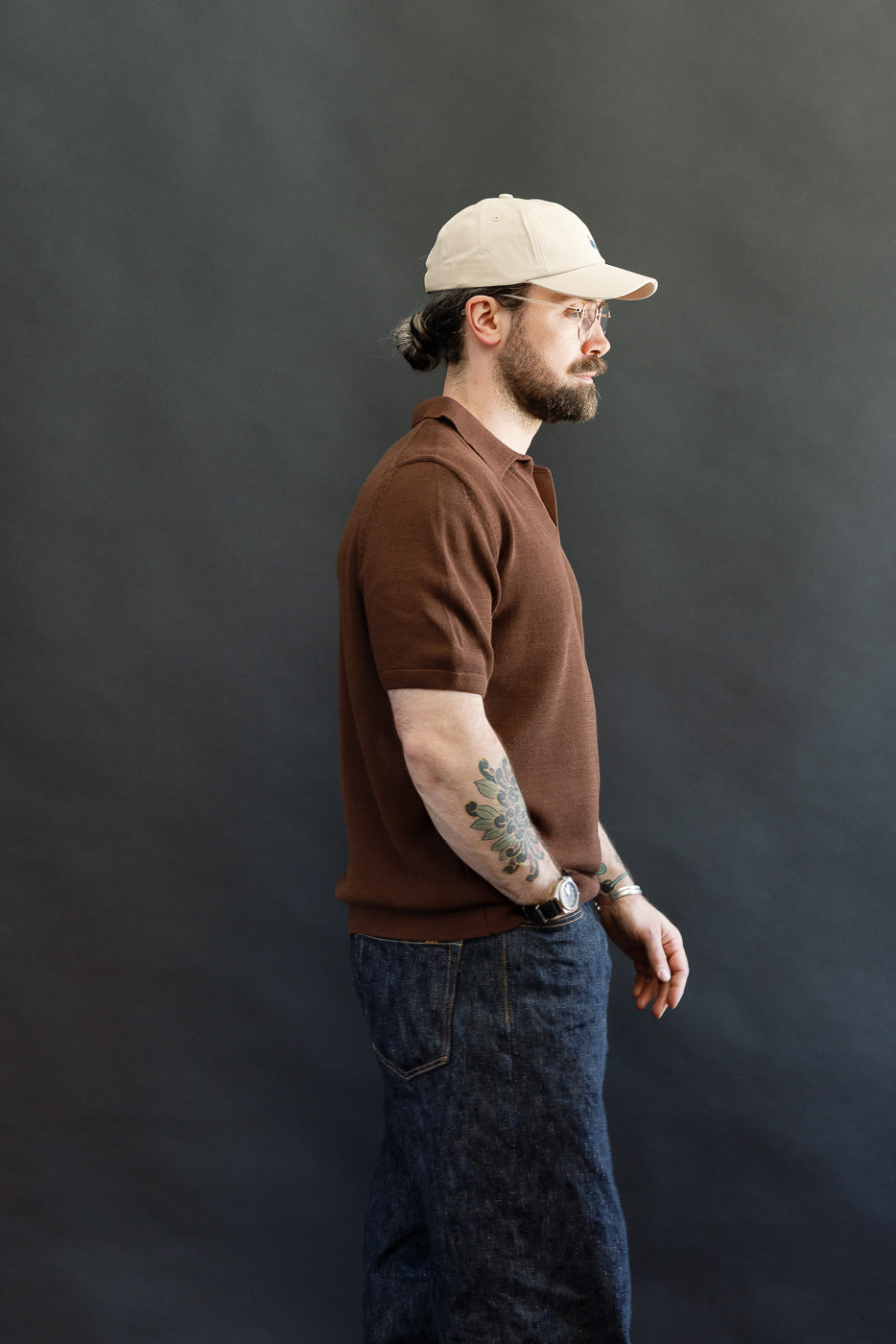 Model wearing the Merz b. Schwanen KNITPOLO02.192.7 - Cotton Short Sleeve Polo Shirt, All Plant Based - Chocolate, showcasing its soft knit texture, relaxed fit, and subtle V-neck with swan embroidery.