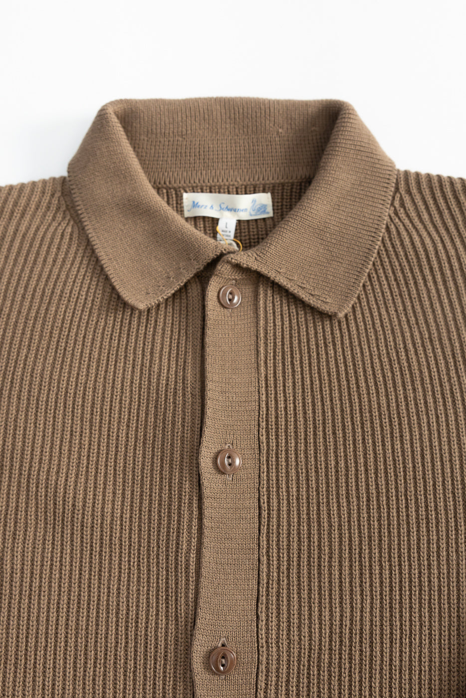 Close-up of front chest and collar on ribbed cotton long sleeve shirt, showing buttons and texture.