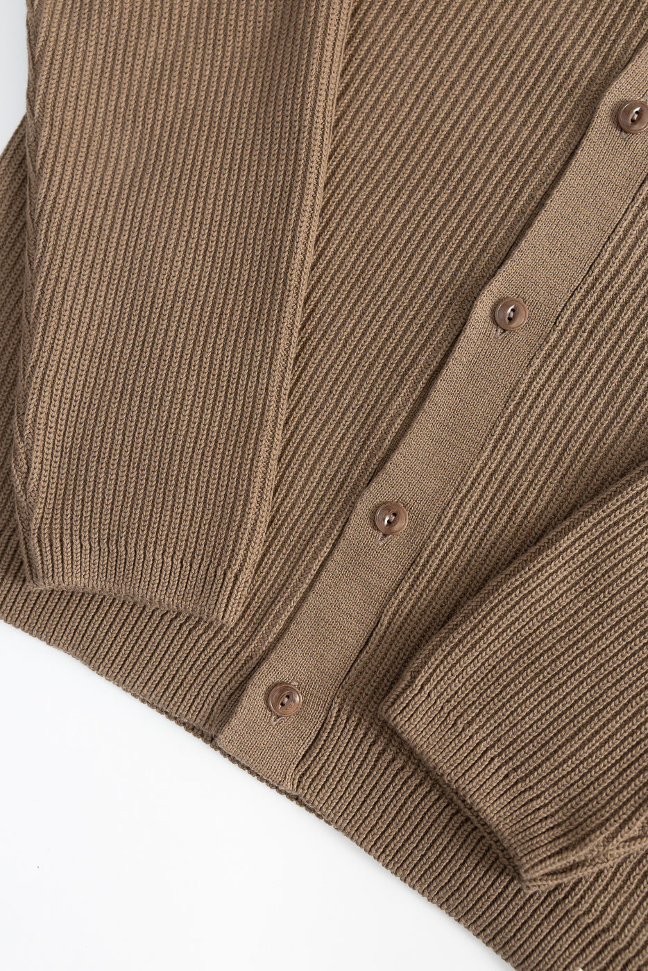 Close-up of front ribbed cotton long sleeve shirt in grain color, showing button placket and sleeve cuff details.