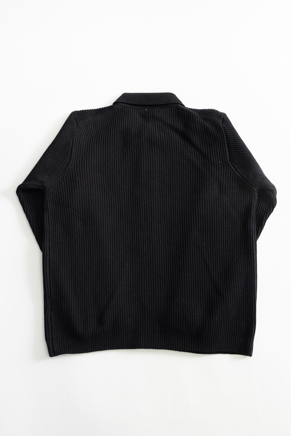 Flat lay of back of deep black ribbed cotton long sleeve shirt, showing collar and texture