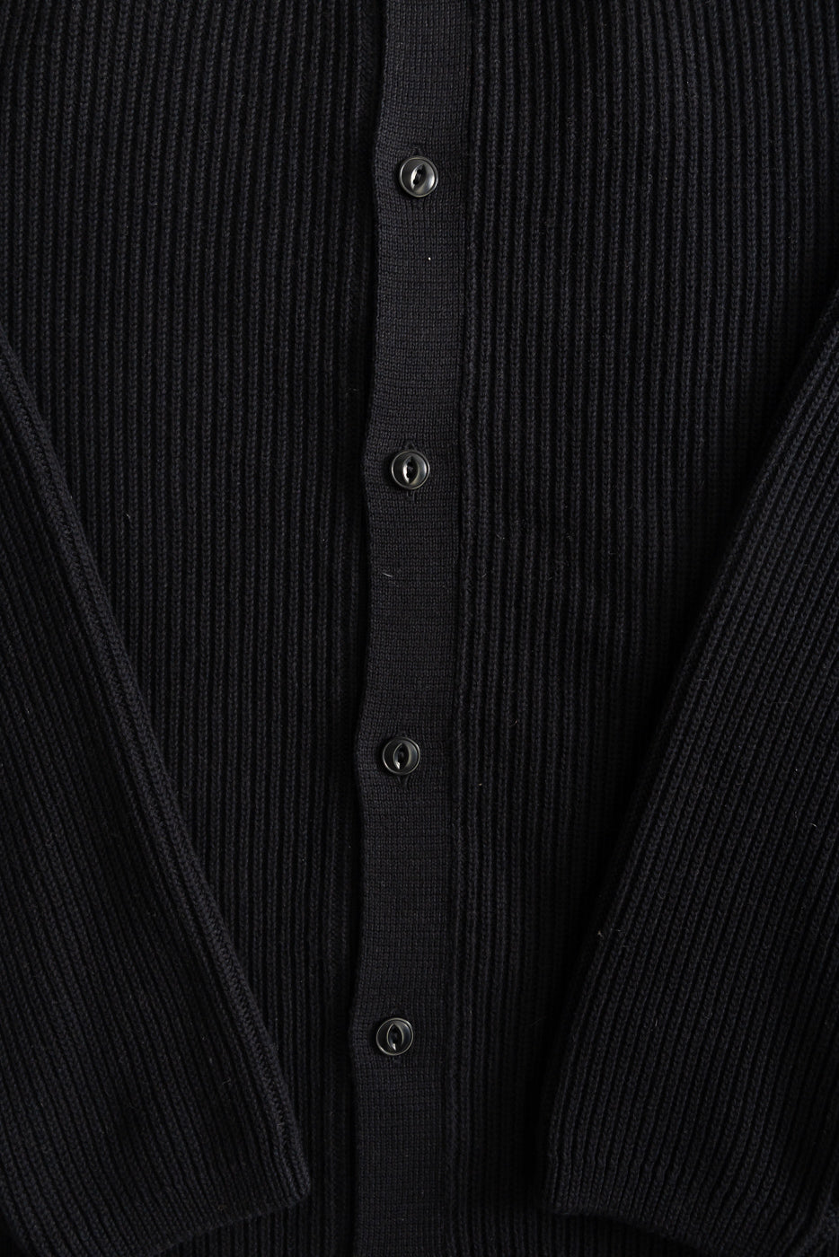 Close-up of front center on ribbed black cotton long sleeve shirt, details of buttons and fabric texture visible.