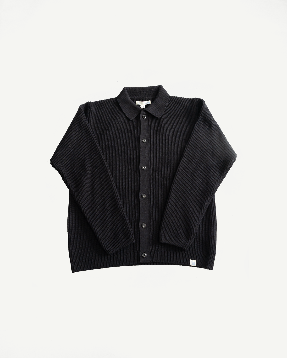 Flat lay, front view deep black ribbed cotton long sleeve shirt with buttons and collar.