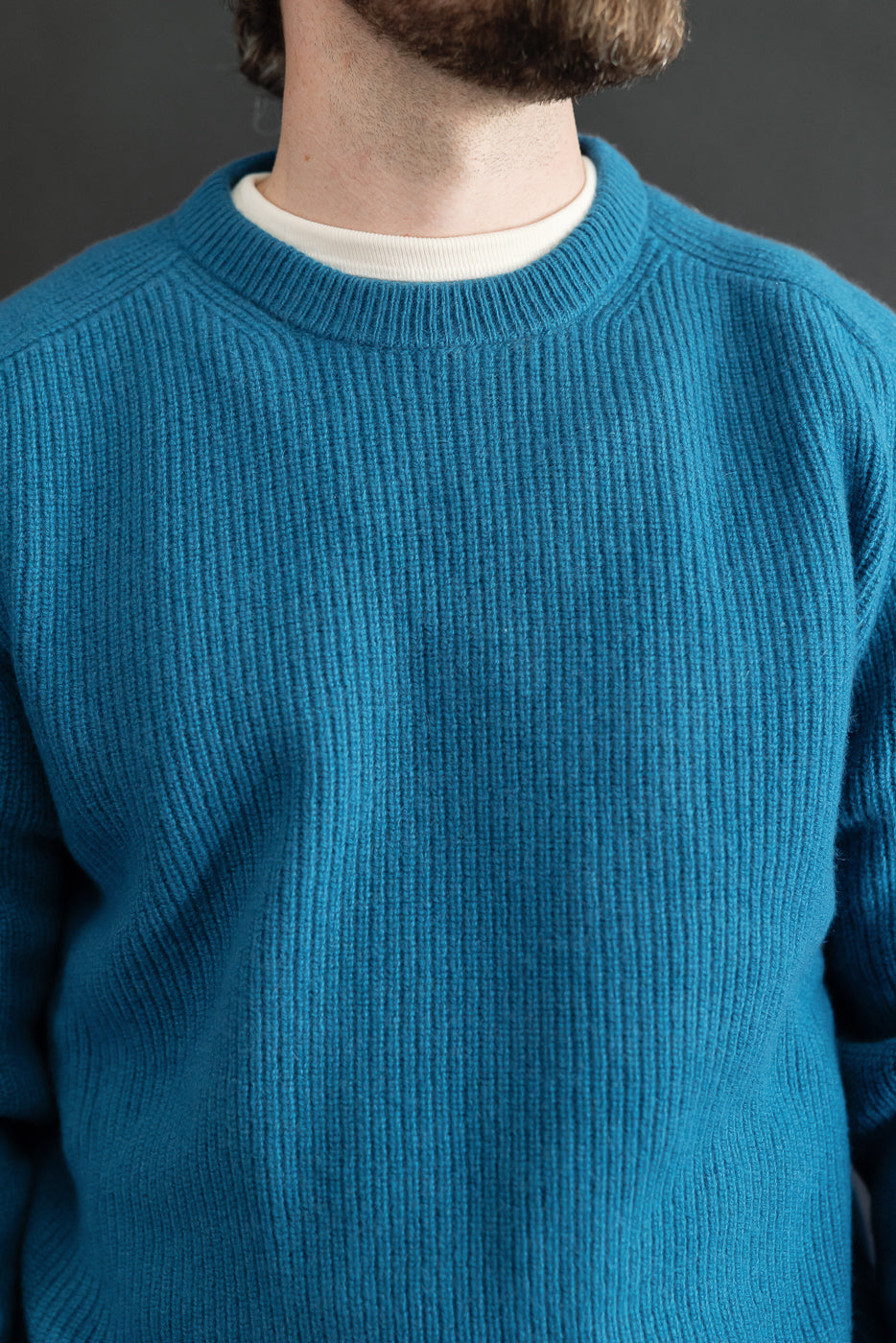 Close-up front view of a blue ribbed sweater on a male model, 5'9