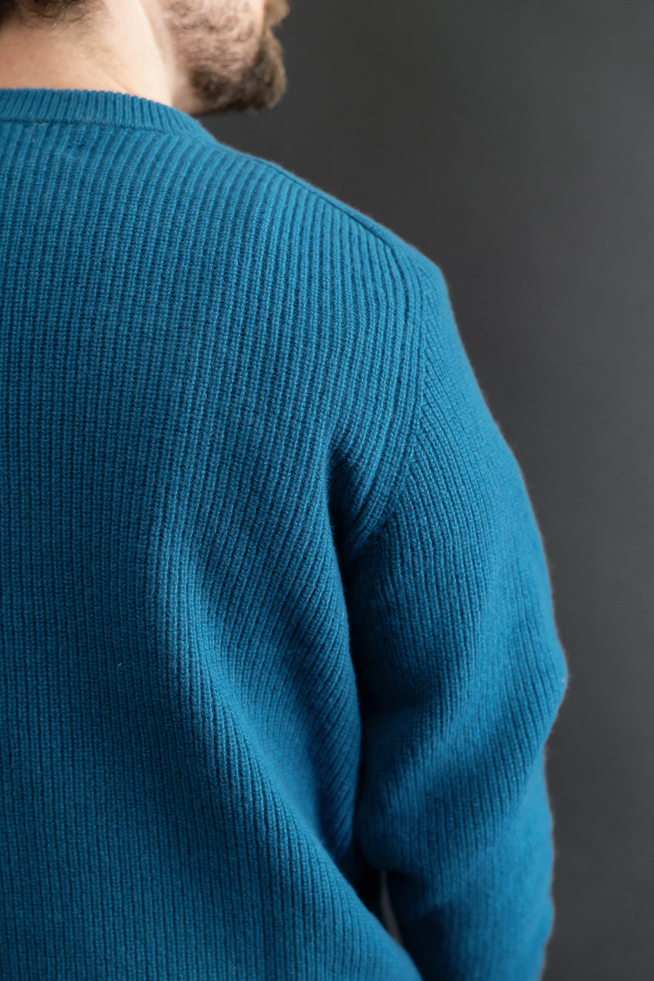 Close-up of the back and shoulder of a teal ribbed sweater on a male model, 5'9
