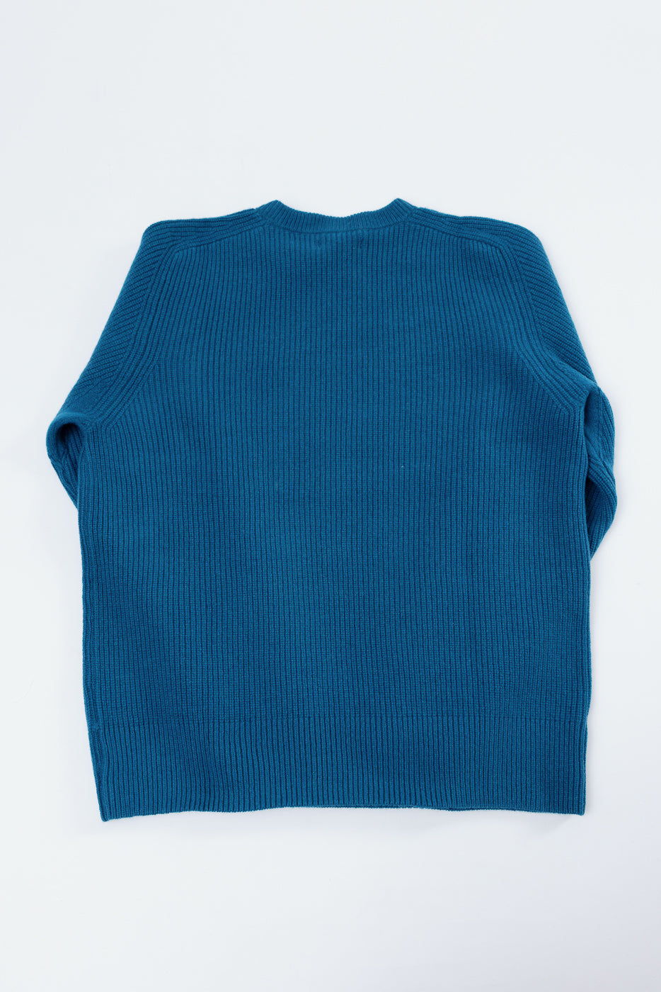 Flat lay view of the back of a blue ribbed knit sweater.