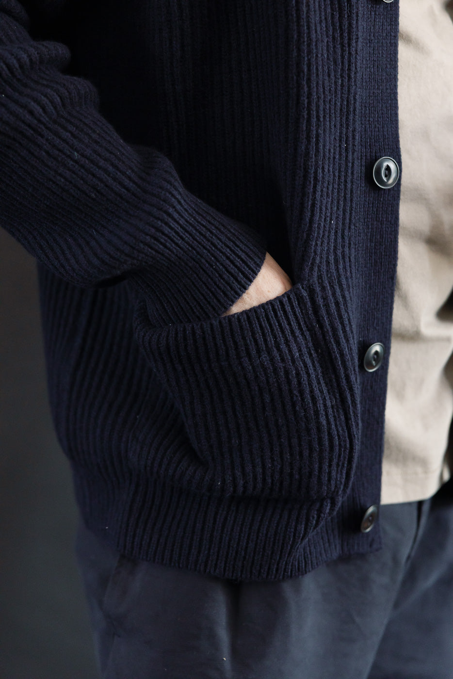Close-up of male model wearing navy Merz b. Schwanen merino wool cashmere cardigan, left side pocket and button details, athletic build, 5'9