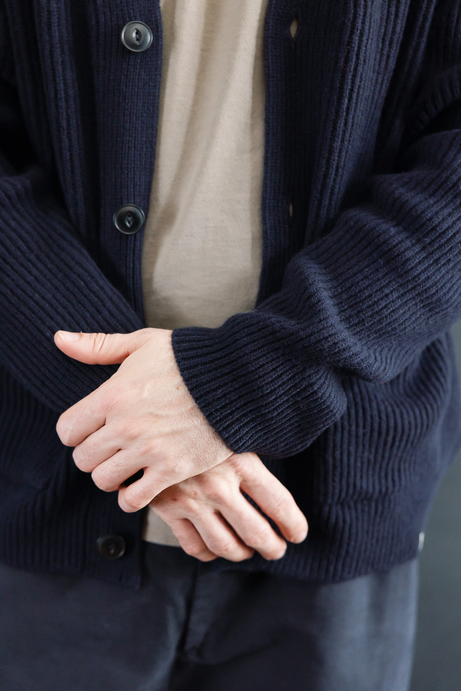 Close-up front of navy Merz b. Schwanen merino wool cashmere cardigan on 5'9 male model, showing ribbed texture and button detail.