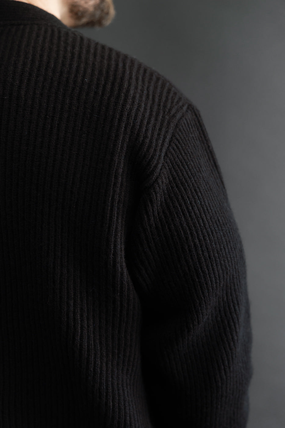 Close-up of the back and right shoulder of a black ribbed knit sweater.