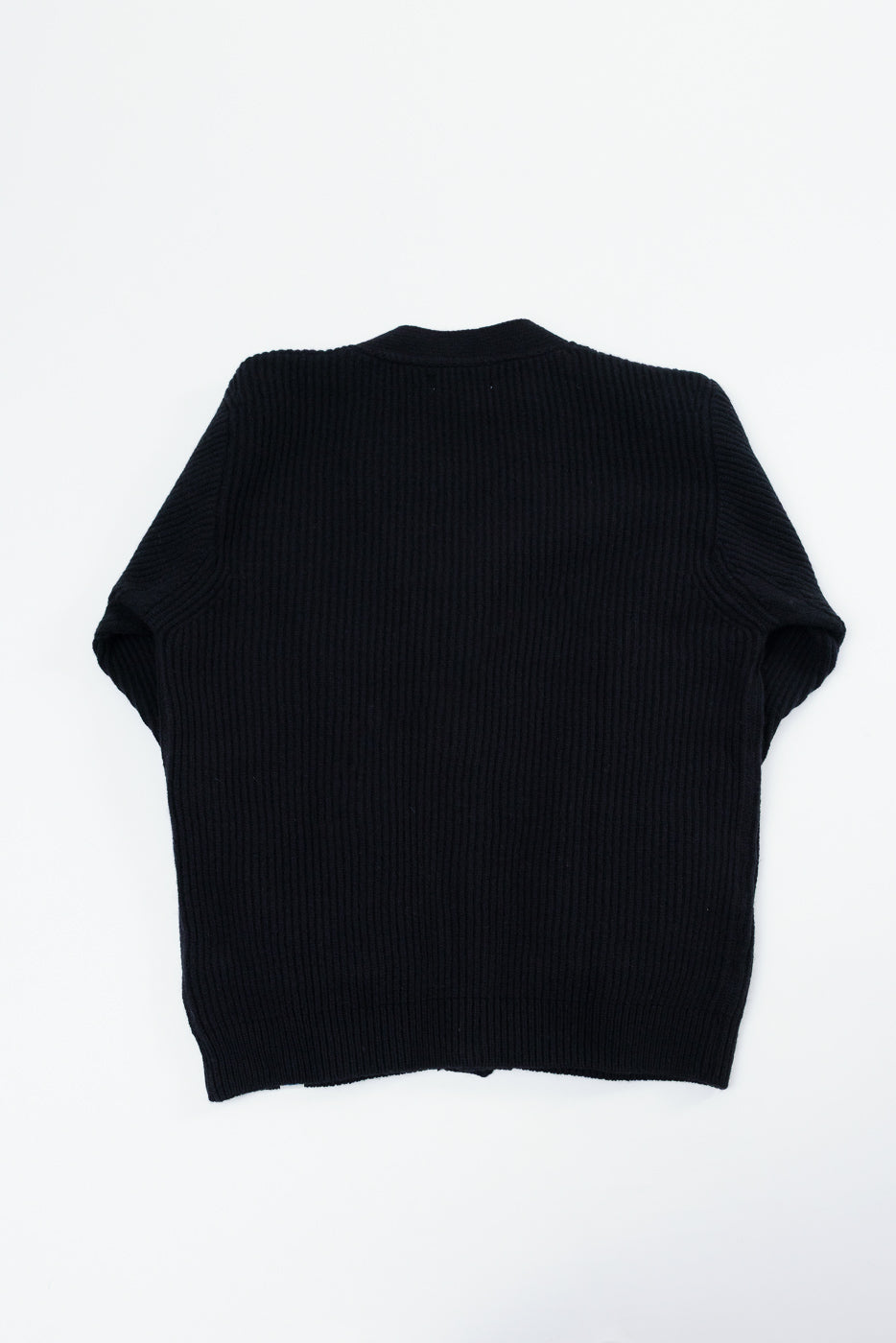 Flat lay of the back of a black ribbed knit sweater.