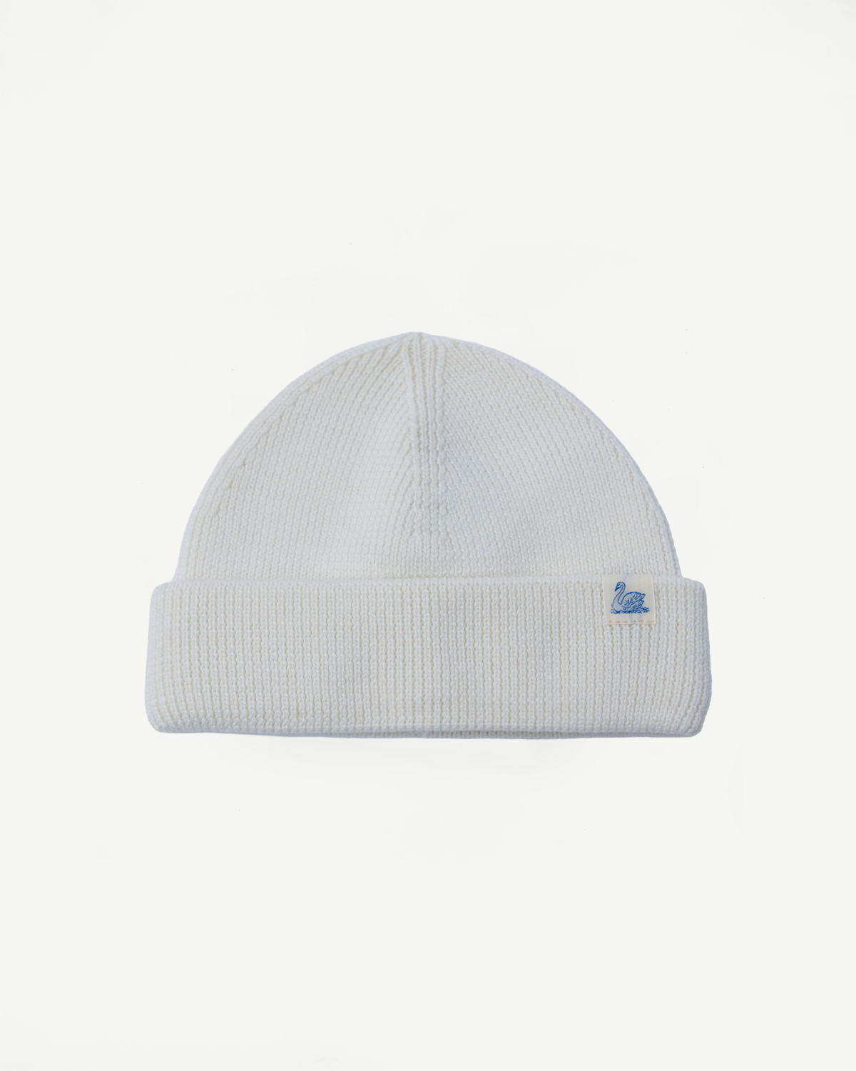 Front view flat lay of Merz b. Schwanen ribbed merino wool watch cap in natural white, visible swan logo tag.